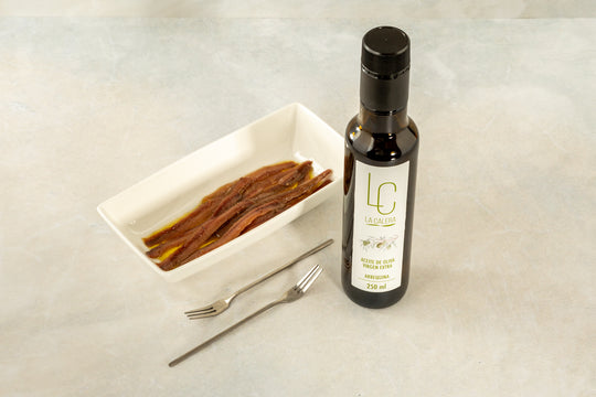 Bodegón de botella de aceite de oliva virgen extra y cuenco con anchoas
